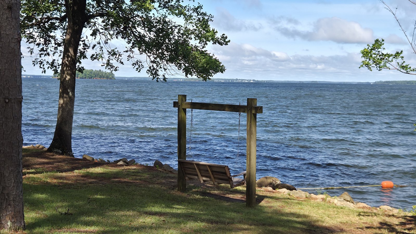 Tree-shaded shoreline and a wooden swing overlooking Lake Murray, South Carolina