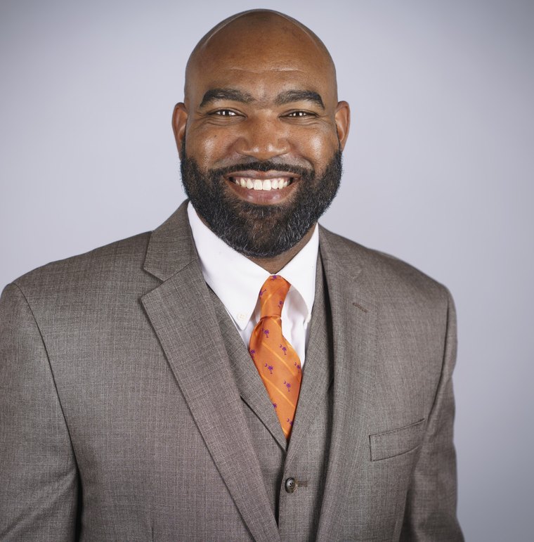 Scott Davis in a gray suit with an orange tie